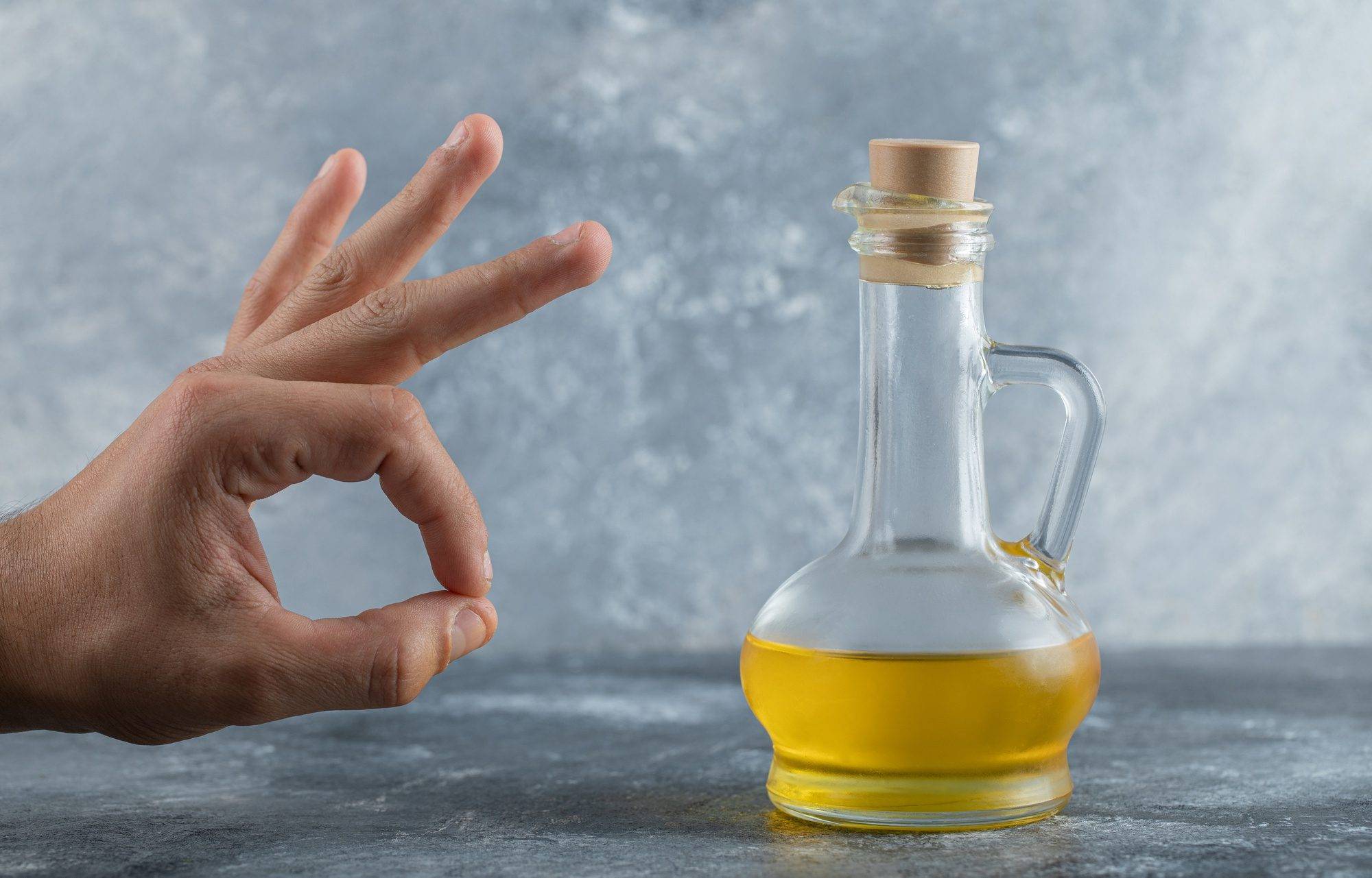 Approval sign over a bottle of StableMAX cooking oil on a gray backdrop.